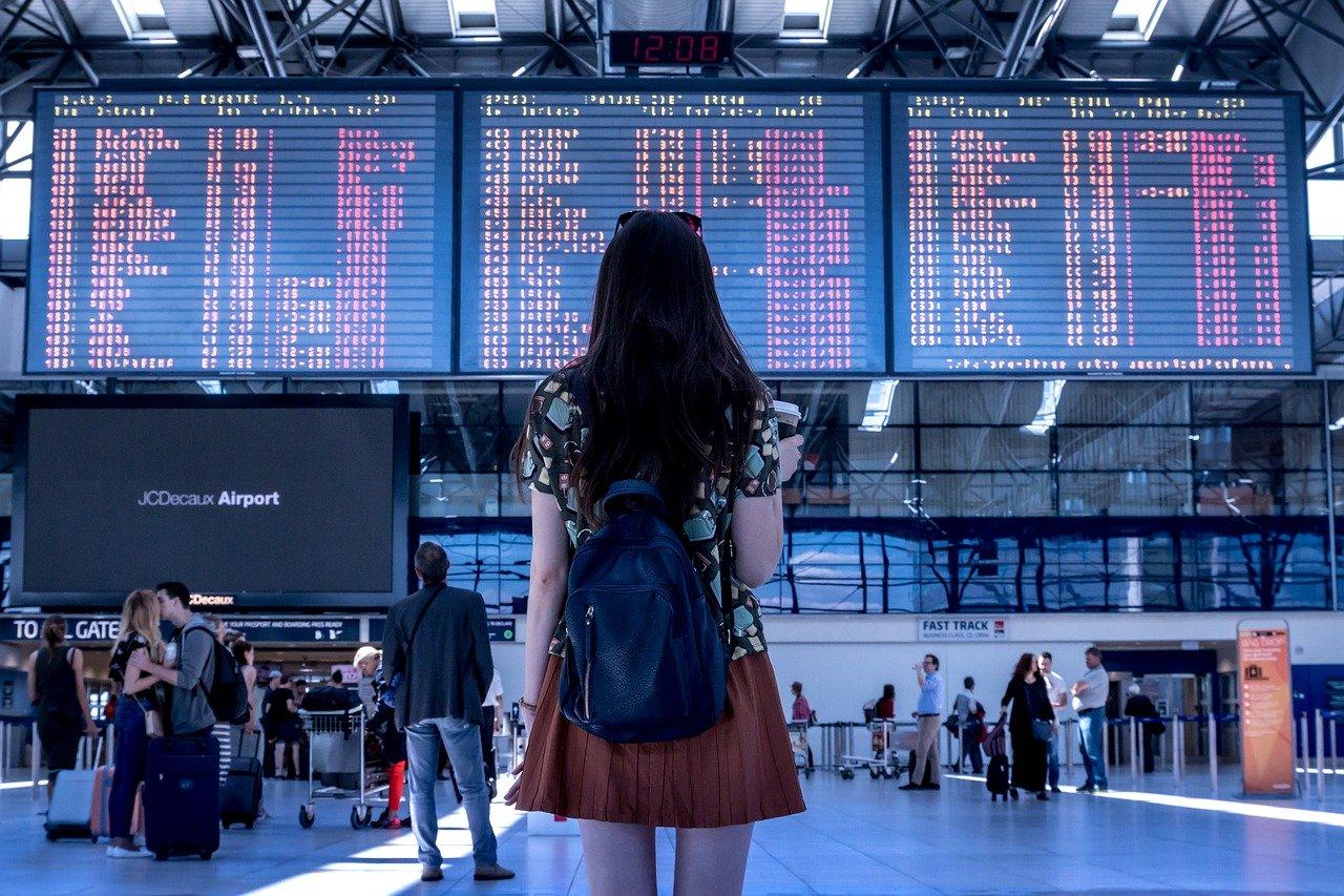 5 Tried and True Thanksgiving Family Travel Tips - young woman looking at airport arrival and departure screens