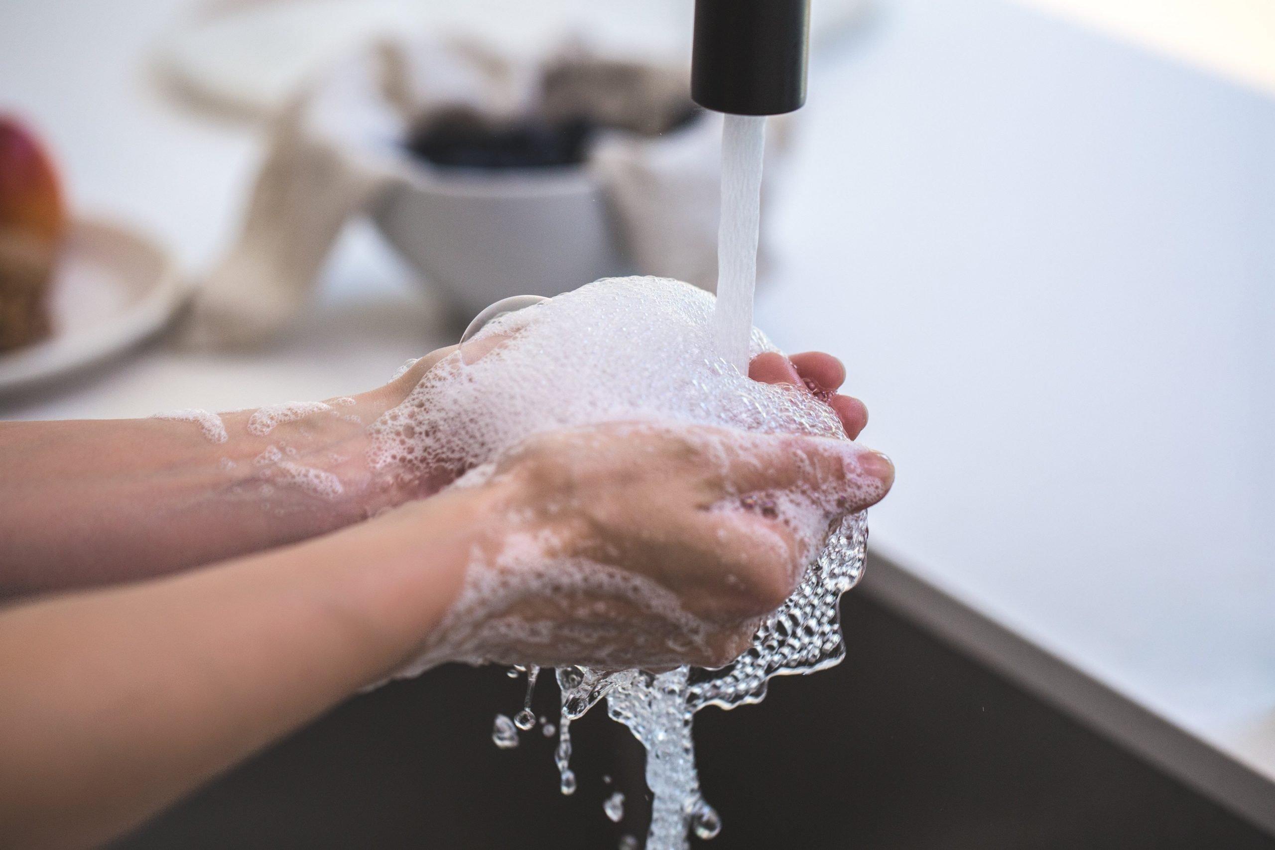 7 Tips to Stay Healthy While Traveling for a Family Vacation - person washing hands to stay healthy while traveling
