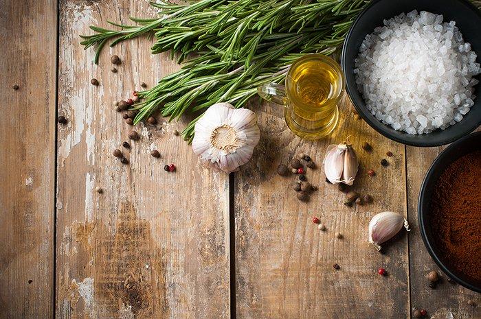 Garlic Festivals to Visit During a Culinary Family Vacation - rustic table with garlic, salt, olive oil, and rosemary